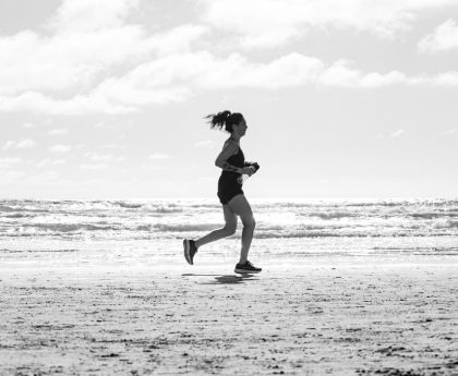 A woman jogging on La Lucila del Mar beach, Argentina in a monochrome setting. Capturing fitness and freedom.